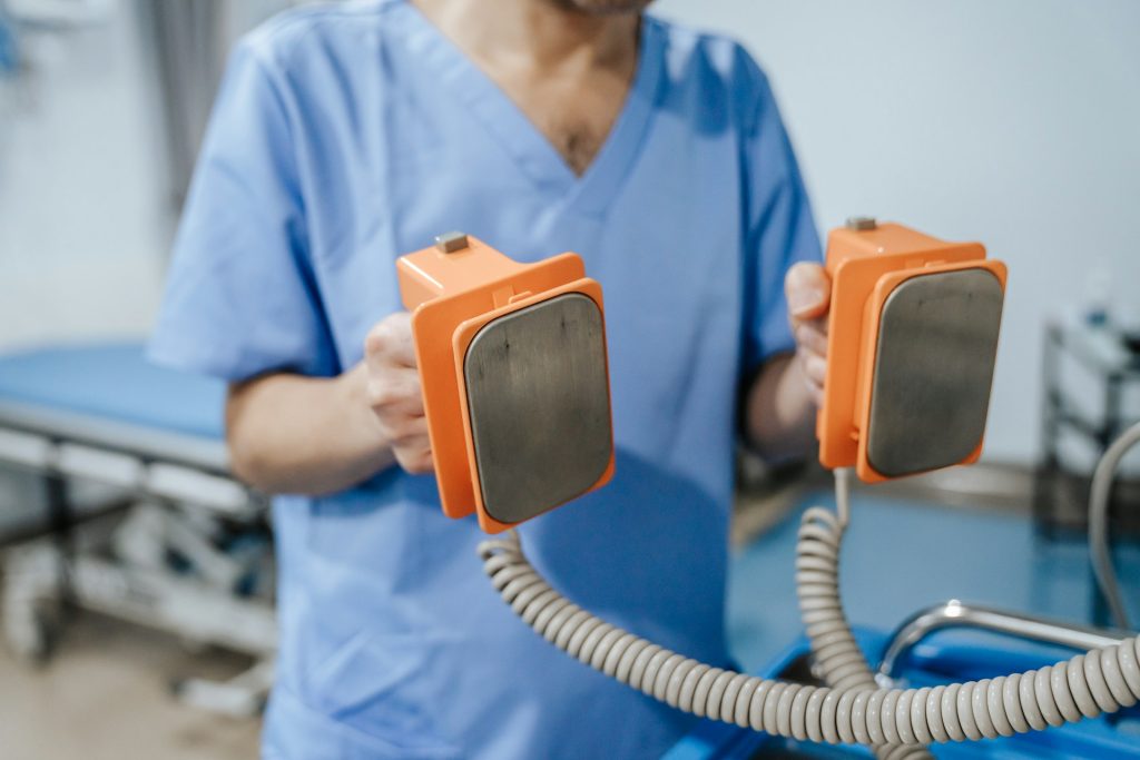 mãos de enfermeiro segurando aparelho de desfibrilação