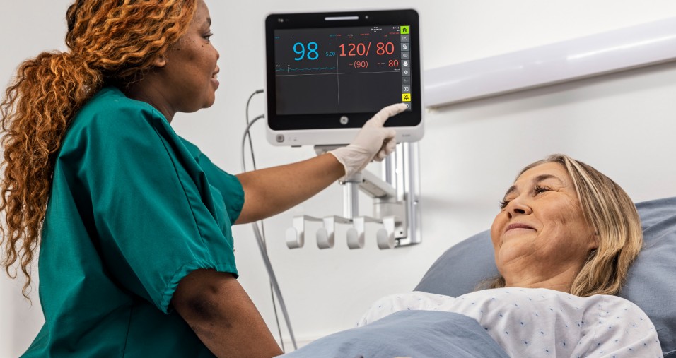 enfermeira ao lado de paciente analisando parâmetro de sinais vitais no monitor da GE Healthcare