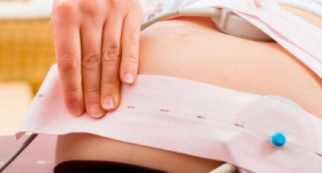 monitor fetal cardiotocógrafo sendo aplicado em barriga de gestante