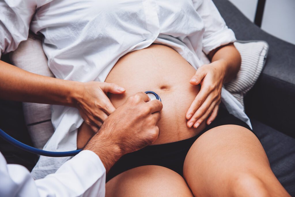 médico checando barriga de mulher grávida com estetoscópio